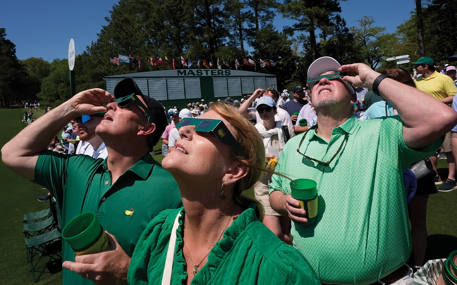 Patrons gaze at the solar eclipse on April 8 during a practice round for the Masters golf tournament in Augusta, Ga.