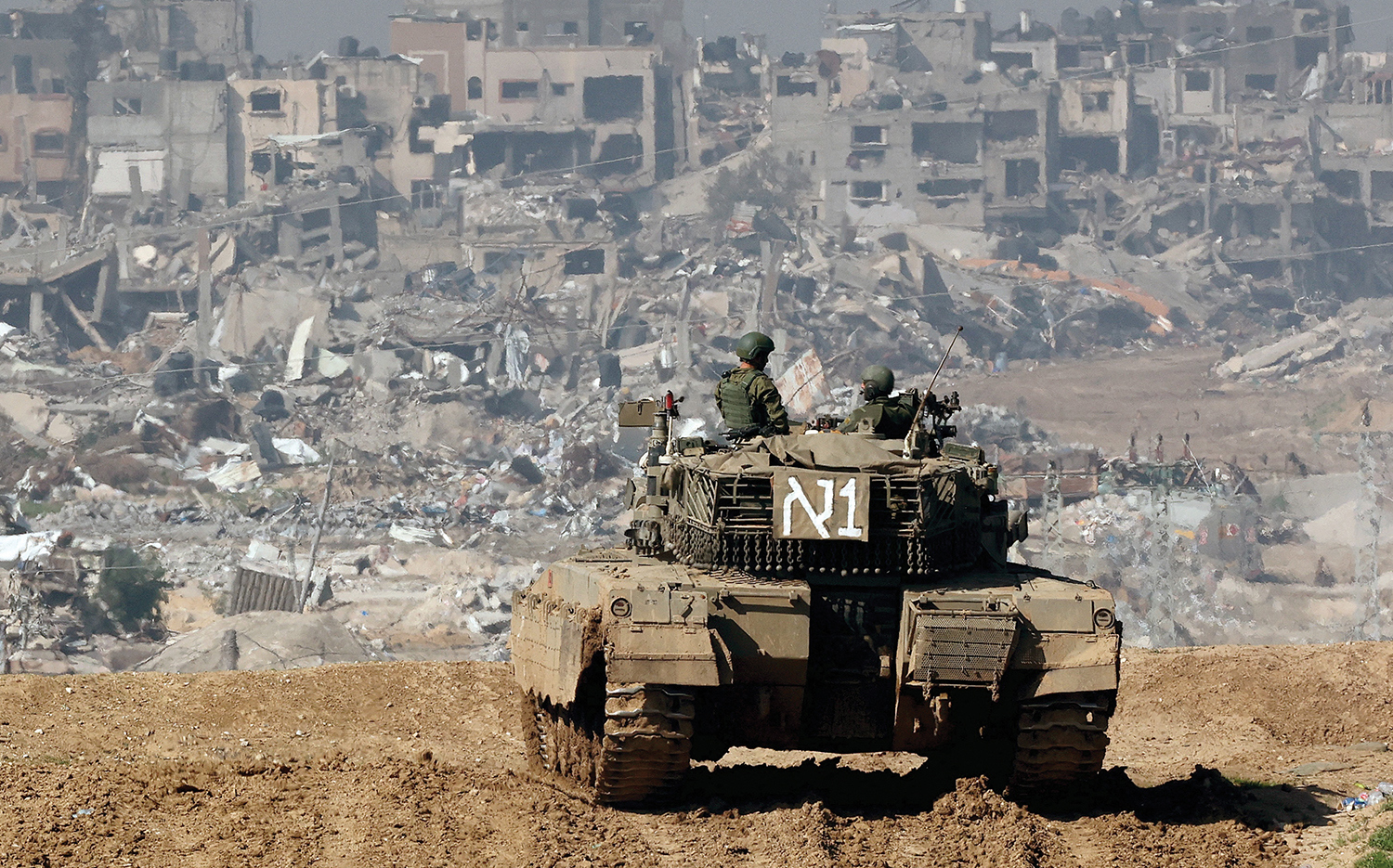 An Israeli tank rolls along the border between Israel and Gaza on Jan. 19, with battle-worn buildings in the background.